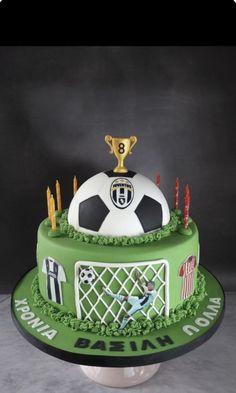 a soccer themed birthday cake with candles and a trophy on top for the ballon d'or winner