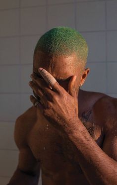 a shirtless man with green hair covering his face