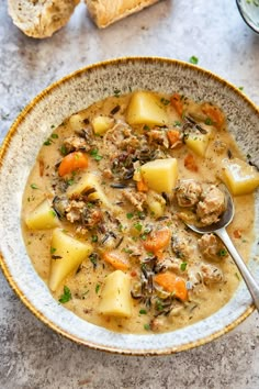 a bowl of soup with meat, potatoes and parmesan bread on the side