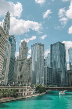 the city is full of tall buildings and blue water with boats floating on it's sides