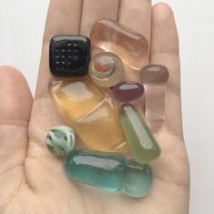 a person's hand holding several different colored rocks