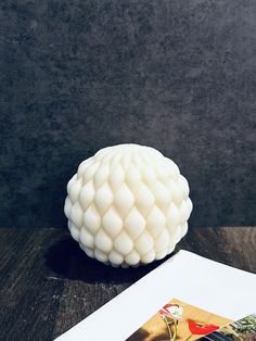 a white vase sitting on top of a wooden table next to an envelope and photo