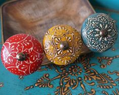 three decorative knobs are sitting on top of a blue and gold tray with an ornate design