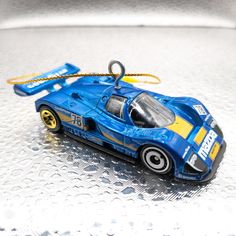 a blue toy car sitting on top of a white table next to a key chain