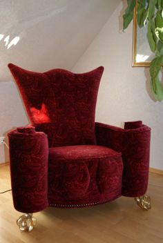 a red chair sitting on top of a wooden floor next to a potted plant