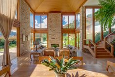 a living room filled with lots of furniture next to a stone wall covered in windows