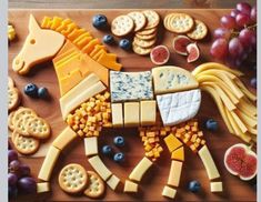 a horse made out of cheese, crackers and grapes on a cutting board with fruit