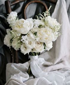 a bouquet of white flowers sitting on top of a bed next to a chair and blanket