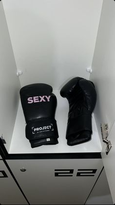 two black boxing gloves sitting on top of a white counter next to eachother