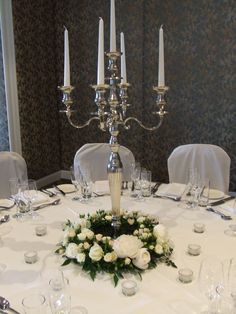 the centerpiece is surrounded by white flowers and silver candelabra with candles