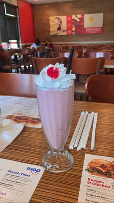 there is a milkshake with whipped cream and strawberries in it on the table