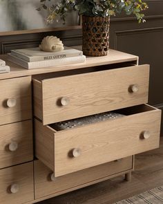 a wooden dresser with two drawers and a potted plant next to it on top