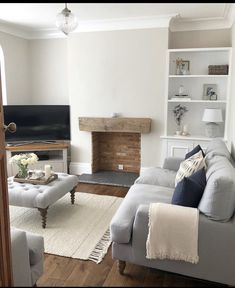 a living room filled with furniture and a flat screen tv mounted on a wall next to a fire place