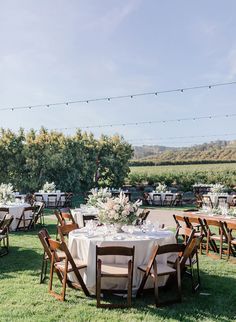 an outdoor wedding reception setup with tables and chairs set up in the grass, surrounded by string lights