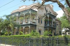 an old house with many windows and balconies on the second floor is surrounded by greenery