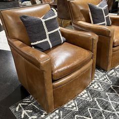 two brown leather chairs sitting on top of a black and white rug next to each other