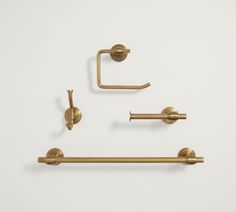 three brass bathroom accessories on a white background, including two handles and one towel bar