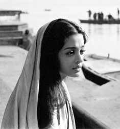 black and white photograph of a woman wrapped in a blanket looking out over the water