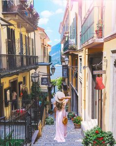 a woman wearing a hat walking down an alley way