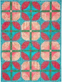 a blue and pink quilt with red circles on the front, green squares in the middle