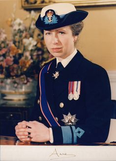 a woman in uniform is sitting at a table with flowers and a vase behind her