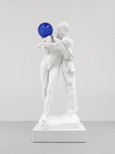 a white statue holding a blue ball in its hand