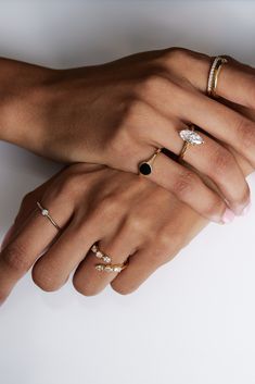 two women's hands holding each other with different rings on their fingers and one has a diamond in the middle