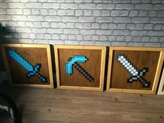 three wooden framed pixel art pieces on a wood floor next to a brick wall with a bike in the background