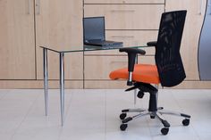 an orange office chair sitting in front of a glass desk