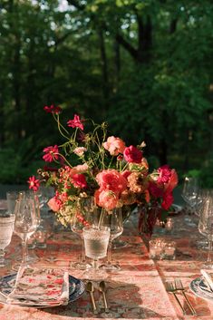 a table topped with lots of glass vases filled with flowers and place settings next to each other