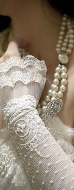 a close up of a woman's hand with pearls and lace on her arm