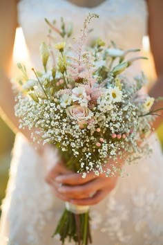 a bride holding a bouquet of white and pink flowers