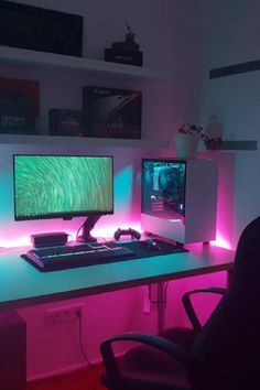 a computer desk with two monitors and a keyboard on it, lit up by neon lights