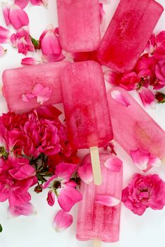 popsicles with pink flowers and petals on a white surface