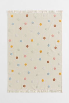 a white blanket with multicolored dots on it