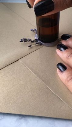 a woman's hands with black nail polish on her nails, next to a brown envelope