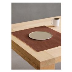 a wooden table topped with a white plate and cup on top of it next to a brown rug