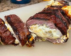 two pieces of meat sitting on top of a cutting board