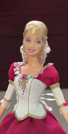 a barbie doll wearing a red and white dress with gold trimmings on it's chest