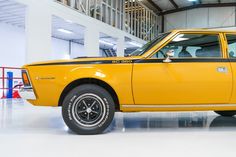 an old yellow car is parked in a garage