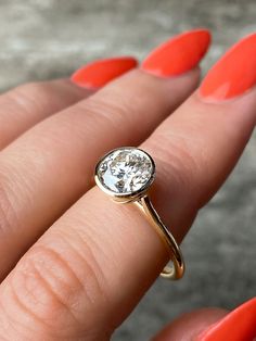 a woman's hand with an orange manicured nail polish holding a diamond ring