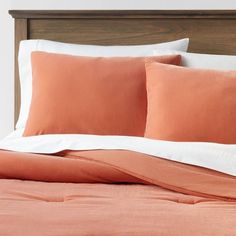 an orange and white bed with two pillows