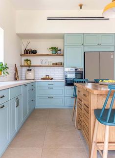 a kitchen filled with lots of blue cabinets and counter top space next to a wooden bar