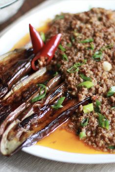 a white plate topped with meat and veggies covered in sauce on top of a table