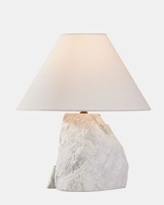 a lamp that is sitting on top of a rock with a white shade over it