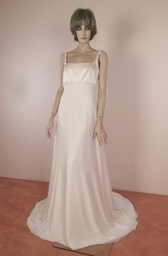 a mannequin wearing a white dress and headpiece in front of a pink wall