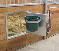 a horse stall with a bucket and hay in it