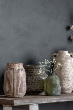 three vases sitting on top of a wooden table next to each other in front of a gray wall