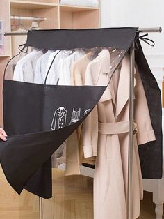 a person holding an umbrella in front of a rack with coats and jackets on it