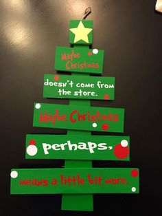 a christmas tree made out of green paper with red and white writing on it, sitting on a table